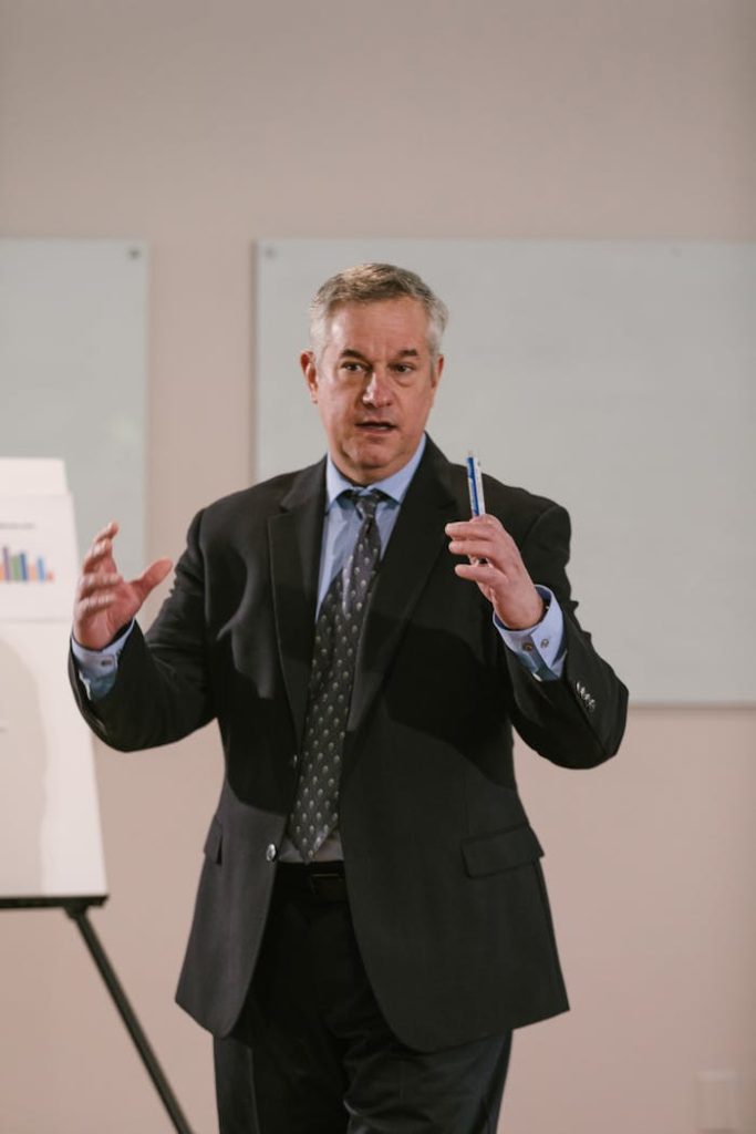 A businessman in corporate attire delivering a presentation indoors.