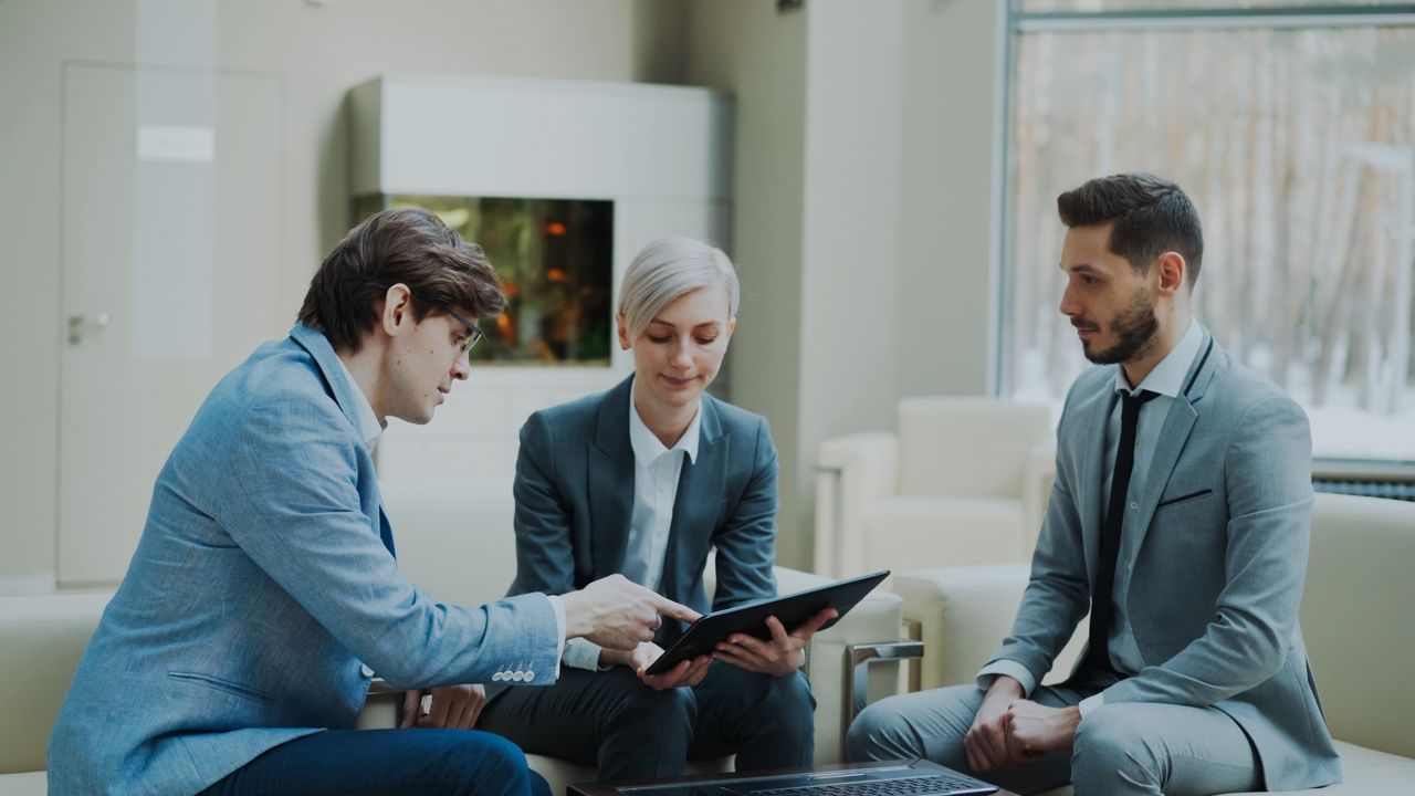 gallery-04 Three professionals engaging in a business meeting in a modern office setting.